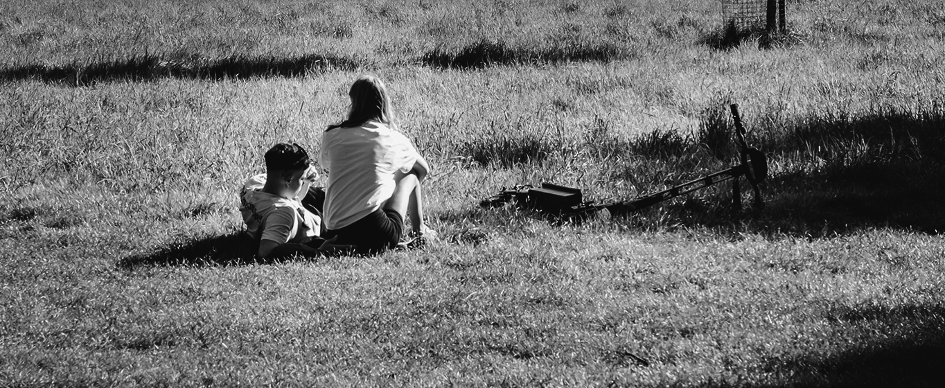 In a field A couple in the distance relaxes in a field of grass